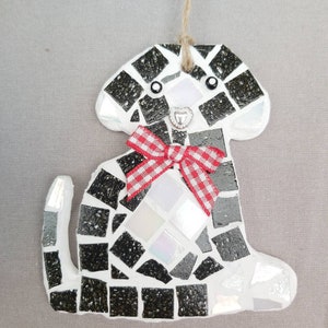 May include: Black and white mosaic dog ornament with a red and white gingham bow. The dog has a white heart on its chest and black eyes.