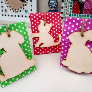 May include: Three gift bags with wooden cutouts of a cat, dog, and rabbit. The bags are decorated with polka dots in red, green, and pink.