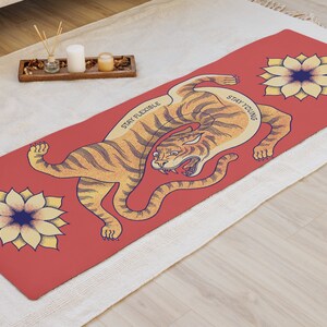 May include: Red yoga mat with a tiger illustration and two yellow flowers. The tiger is in a curled position with the text "Stay Flexible" and "Stay Young" on the mat.