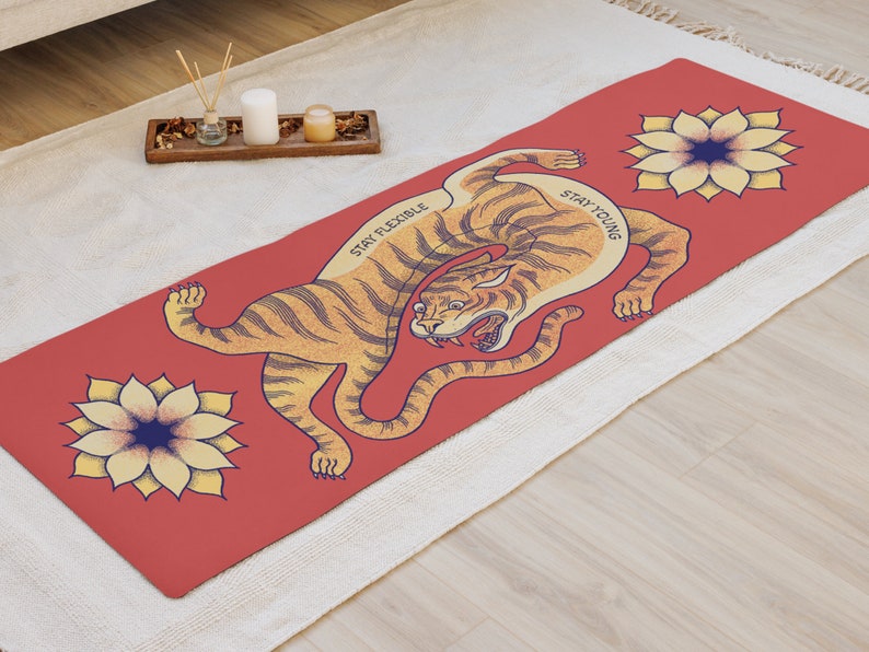 May include: Red yoga mat with a tiger illustration and two yellow flowers. The tiger is in a curled position with the text "Stay Flexible" and "Stay Young" on the mat.