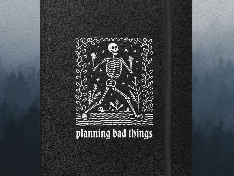 May include: Black notebook with a white illustration of a skeleton in a forest setting. The text "planning bad things" is printed below the illustration.