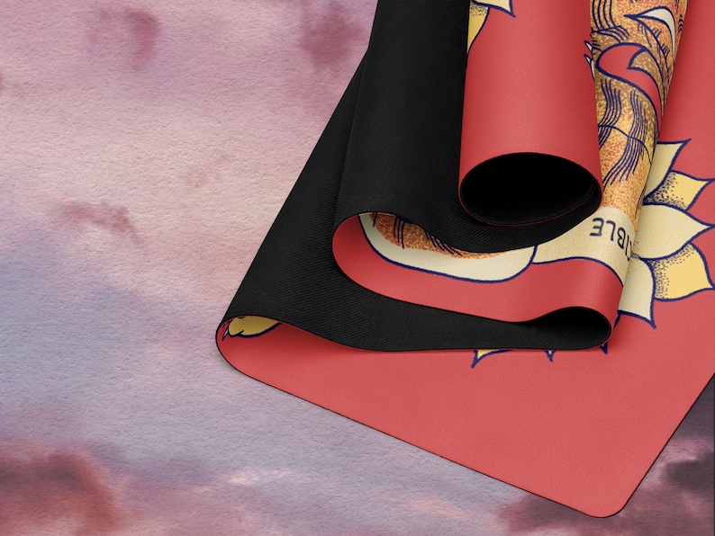 May include: A red yoga mat with a yellow and white floral design and the word "IBLE" printed on the side. The mat is rolled up and the black underside is visible.