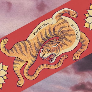 May include: A red background with a stylized illustration of a tiger in a curled position. The tiger is orange and black with a white belly. The text "Stay Flexible" and "Stay Young" is written on the tiger's body. There are two yellow flowers with black centers on the background.