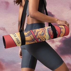 May include: A red and yellow yoga mat with a black strap and the text "Stay Flexy" printed on it. The mat is rolled up and being carried by a person.