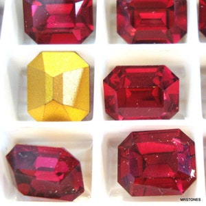 May include: Assortment of red and gold glass gems in a white plastic tray. The gems are rectangular and have a faceted design.