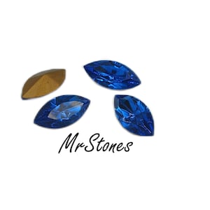 May include: Four marquise-shaped blue glass rhinestones. The rhinestones are arranged in a loose circle with one rhinestone at the top and the other three at the bottom. The rhinestones are on a white background. Mr. Stones is written in black text below the rhinestones.