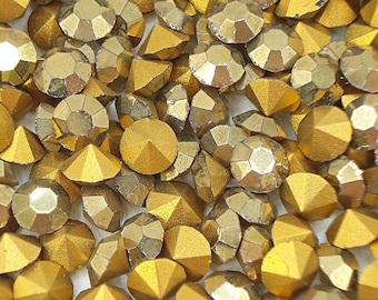 May include: A close-up of a large quantity of gold-colored rhinestones. The rhinestones are faceted and have a shiny finish.
