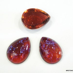 以下が含まれることがあります： 涙の形をしたガラスのカボションが3つあります。1つは透明な濃い赤色のガラスで、わずかに光沢があります。他の2つは濃い赤色のガラスで、青色の虹色の光沢があります。