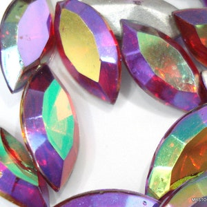 May include: Close-up of iridescent marquise-shaped rhinestones. The rhinestones have a faceted design with a mix of colors, including red, purple, green, and gold. These decorative stones are ideal for jewelry making and crafts.