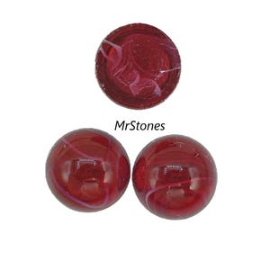 May include: Three red marbles with white swirls and a dark red marble with white swirls. The marbles are glossy and reflect light. The text "MrStones" is visible.