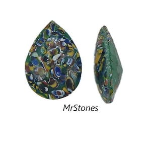 Puede incluir: Una cuenta de vidrio en forma de lágrima con una base verde y un patrón multicolor de azul, amarillo, rojo y blanco. La cuenta se muestra desde dos ángulos.