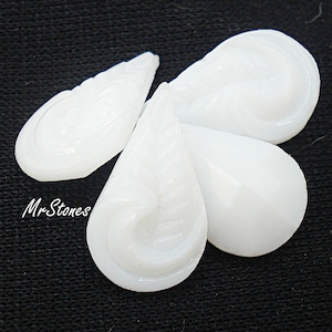 Puede incluir: Cuatro cuentas de vidrio blanco en forma de lágrima con un diseño tallado. Las cuentas son lisas y tienen un acabado brillante.