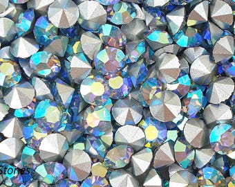 May include: A close-up of a large quantity of iridescent blue and silver rhinestones. The rhinestones are scattered randomly and appear to be of various sizes.
