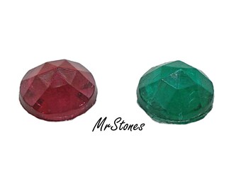 Puede incluir: Dos gemas facetadas: una de color rojo intenso y otra verde esmeralda. Las gemas son redondas con una parte superior abovedada y una superficie multifacética. El texto "MrStones" está escrito en cursiva.