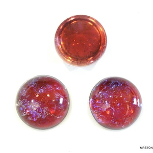 Op de afbeelding: Drie ronde glazen cabochons met een rode en paarse iriserende afwerking. De cabochons zijn ongeveer 2,5 cm in diameter.