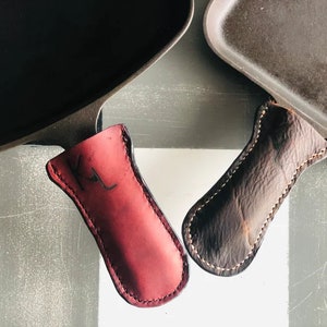 Burgundy oiled leather that is hand cut, punched and stitched, to perfectly fit those classic cast iron pans. They are durable and age well over time. Simply wipe with a damp cloth and let dry thoroughly before the next use.