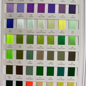 May include: A colour chart displaying a range of satin ribbons in hues of purple, green, yellow, and orange. Each ribbon is labelled with a colour name and number, like "Lilac Mist" and "Neon Orange". The ribbons are arranged in vertical columns.