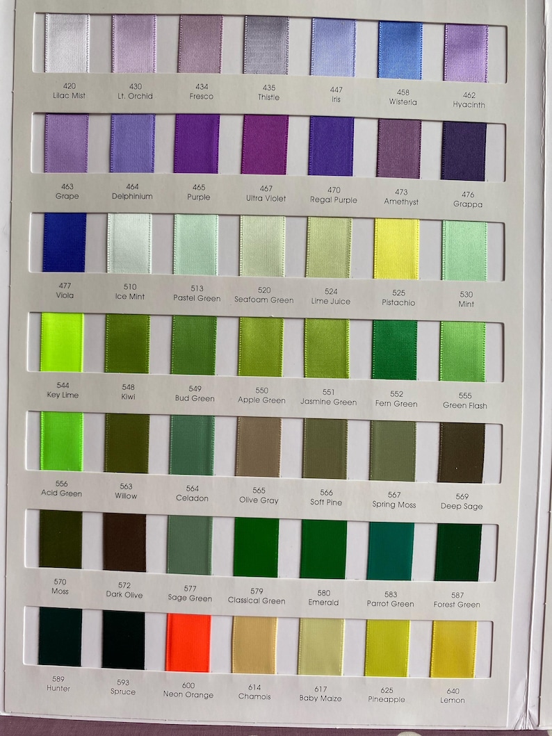 May include: A colour chart displaying a range of satin ribbons in hues of purple, green, yellow, and orange. Each ribbon is labelled with a colour name and number, like "Lilac Mist" and "Neon Orange". The ribbons are arranged in vertical columns.