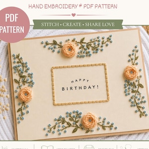 May include: A PDF pattern for a floral birthday card featuring hand embroidery. The card displays peach-coloured roses and blue sprigs with green leaves. A central rectangular frame surrounds the text HAPPY BIRTHDAY! in black capital letters.