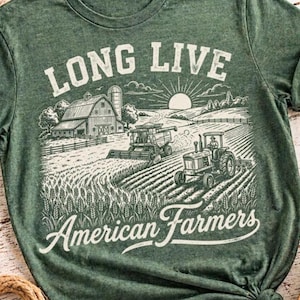 May include: Green t-shirt with a graphic design featuring a farm scene with a barn, tractor, and combine harvester. The text "LONG LIVE American Farmers" is printed in white, vintage-style lettering.