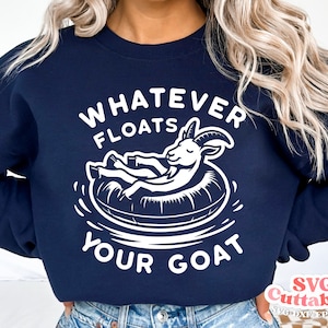以下が含まれることがあります： 白い文字で「Whatever Floats Your Goat」と書かれたネイビーブルーのスウェットシャツ。白い浮き輪に乗ったヤギのイラストがスウェットシャツの中央に描かれています。