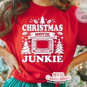 May include: Red t-shirt with white text that reads "Christmas Movie Junkie" with a stylized TV and Christmas trees.
