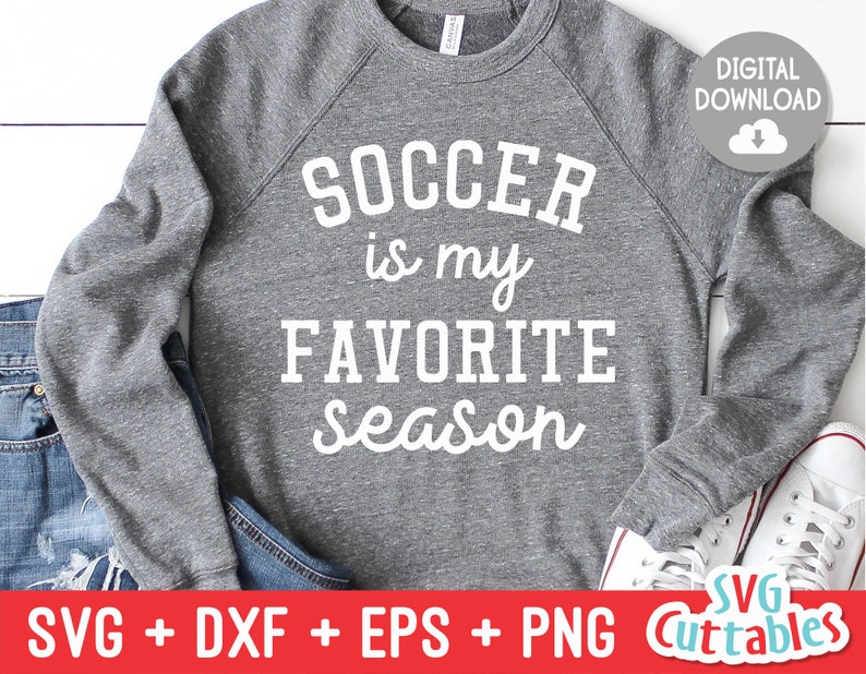 May include: Gray sweatshirt with the text "SOCCER is my FAVORITE Season" in white lettering. The sweatshirt is laying on a pair of jeans and a white shoe.