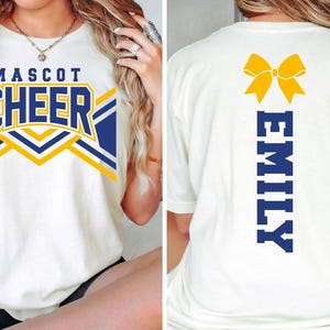 May include: A white t-shirt featuring a front graphic with the text MASCOT CHEER in blue and yellow, and a back graphic with a yellow bow icon above the vertical blue text EMILY. The shirt has short sleeves and a crew neckline, shown from both sides.