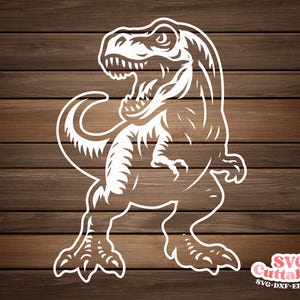 May include: White cut-out design of a Tyrannosaurus Rex dinosaur with open mouth and detailed features. The dinosaur is set against a brown wood grain background. The image includes the text "SVG Cuttables" and file type abbreviations.