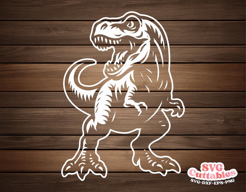 May include: White cut-out design of a Tyrannosaurus Rex dinosaur with open mouth and detailed features. The dinosaur is set against a brown wood grain background. The image includes the text "SVG Cuttables" and file type abbreviations.