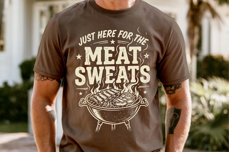 May include: Brown t-shirt with the text "JUST HERE FOR THE MEAT SWEATS" in a distressed font. The graphic features a grill with ribs and a steak. The shirt is short-sleeved.