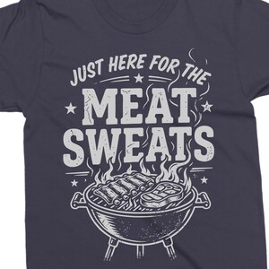 May include: Dark navy blue t-shirt with the text "JUST HERE FOR THE MEAT SWEATS" in white. The graphic includes a grill with ribs and a steak, flames, and stars.