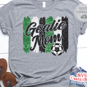 May include: A gray t-shirt with a black and green glitter design that says "Goalie Mom" with a soccer ball in the center.