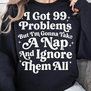 May include: Black sweatshirt featuring the white text "I Got 99 Problems But I'm Gonna Take A Nap And Ignore Them All". The design includes star accents.