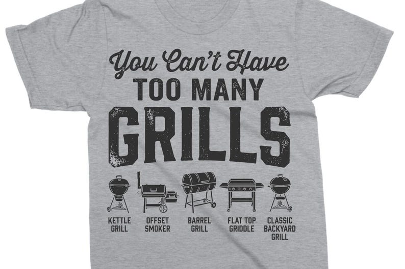 May include: A heather gray t-shirt with the text "You Can't Have Too Many Grills" in black. Below the text are illustrations of different grill types, including kettle, offset smoker, barrel, flat top griddle, and classic backyard grill.