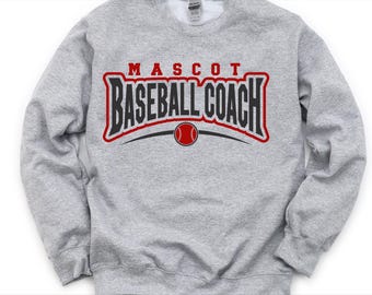 May include: A light gray sweatshirt with the words "MASCOT BASEBALL COACH" in a red and black design. A red baseball is centered below the text, with a black curved line on each side.