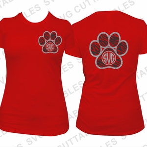 May include: Two red t-shirts with a silver glitter paw print design. The paw print has a black and white zebra print inside and the letters "SVG" in the center.