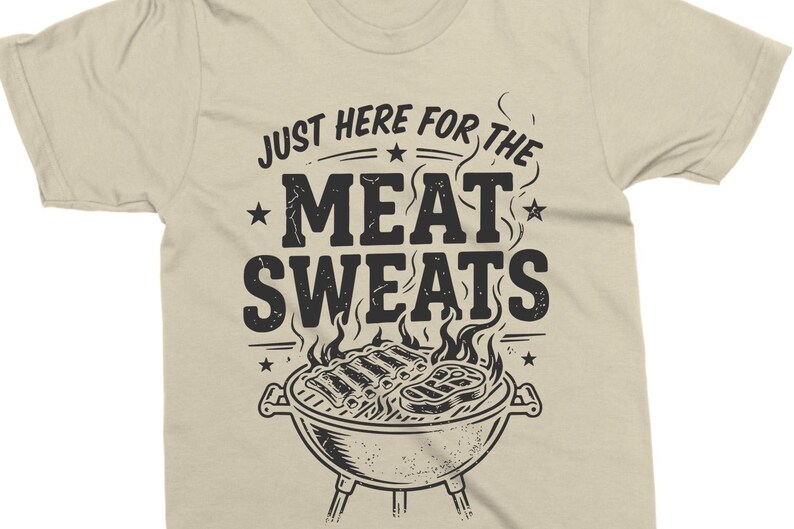 May include: Beige t-shirt with a black graphic. The graphic features the text "JUST HERE FOR THE MEAT SWEATS" above a drawing of a barbecue grill with ribs and steak. The shirt is made of a soft material.