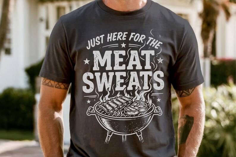 May include: Dark gray t-shirt with the text "JUST HERE FOR THE MEAT SWEATS" in white, along with a graphic of a grill with ribs and steak. The shirt is short-sleeved.