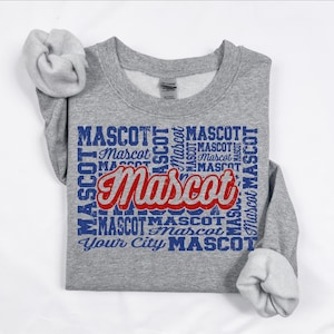 May include: A gray sweatshirt with the word "Mascot" in a red and blue design. The word "Mascot" is repeated in a blue font around the main text. The sweatshirt has rolled-up sleeves.
