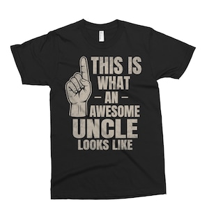 May include: Black t-shirt with a white graphic that says "This is what an awesome uncle looks like". The graphic also includes a hand with a finger pointing up.