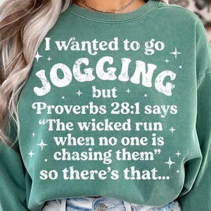 May include: A teal green sweatshirt with the text "I wanted to go JOGGING but Proverbs 28:1 says 'The wicked run when no one is chasing them' so there's that..." in white. The sweatshirt has a crew neck and long sleeves.
