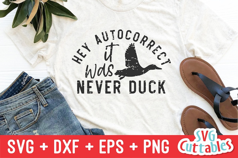 May include: A white t-shirt with the text "Hey it was never duck" in black lettering. The text is in a distressed font and includes a black silhouette of a duck.
