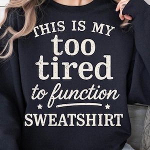 May include: Black sweatshirt with the text "THIS IS MY too tired to function SWEATSHIRT" in white distressed font. The text is arranged in a stacked format, with stars on either side of the word "function".