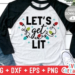 以下が含まれることがあります： 白と黒のラグランスリーブTシャツに、黒い文字で「Let's get lit」と書いてあり、その周りをカラフルなクリスマスライトの紐が囲んでいます。