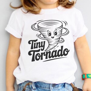 Peut inclure: T-shirt blanc avec un dessin de tornade noire et blanche souriante et le texte "Tiny Tornado". Le v&ecirc;tement est port&eacute; par un enfant. Id&eacute;al pour les enfants.