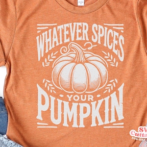 May include: Orange t-shirt with the text "WHATEVER SPICES YOUR PUMPKIN" in white, featuring a pumpkin illustration. The shirt is a fall-themed design, perfect for the autumn season.