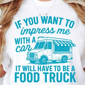 May include: White t-shirt with a teal graphic of a food truck and the text "IF YOU WANT TO impress me WITH A car IT WILL HAVE TO BE A FOOD TRUCK". The design is a fun statement for food truck enthusiasts.