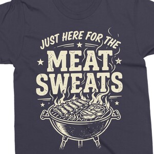 May include: Dark navy blue t-shirt with a barbecue grill graphic. The text "JUST HERE FOR THE MEAT SWEATS" is printed above the grill. The grill contains ribs and a steak, with flames and smoke.