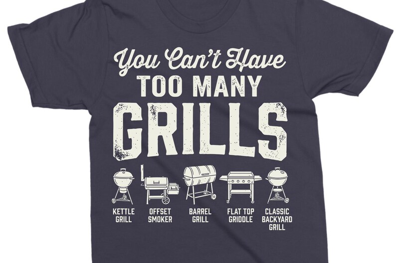 May include: Dark blue t-shirt with the text "You Can't Have Too Many Grills" in white. Below the text are illustrations of different grill types, including kettle, offset smoker, barrel, flat top griddle, and classic backyard grill.
